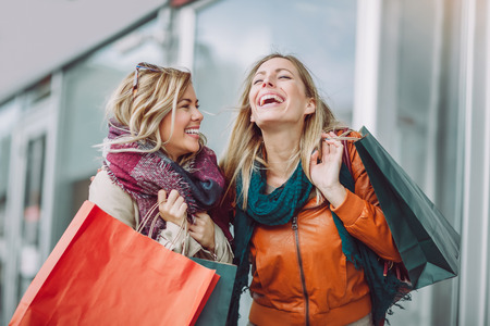 Happy friends shopping. Two beautiful young women enjoying shopping in the city.の写真素材