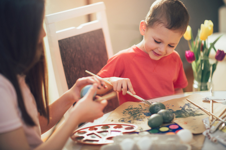 Brother and sister painted Easter eggs at the tableの写真素材