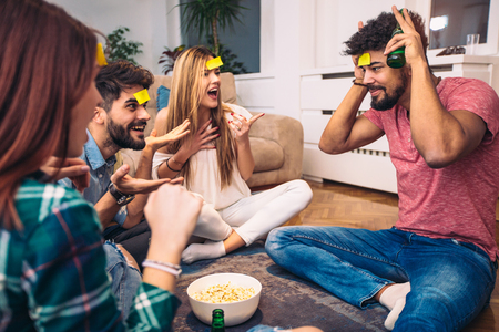 Happy friends playing game guess who and having fun at homeの写真素材