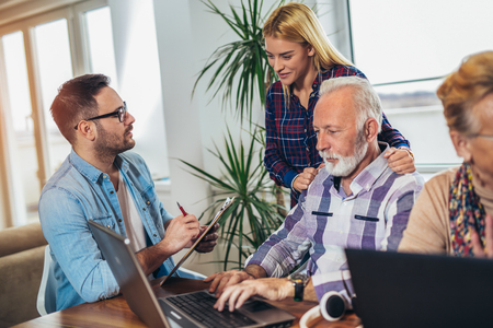 Young volunteers help senior people on the computer. Young people giving senior people introduction to internetの写真素材