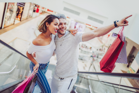  Happy young couple with shopping bags walking in mall - sale, consumerism and people concept の写真素材