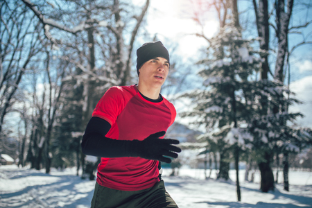 Young man running at winter in parkの写真素材