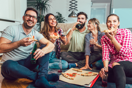 Group of young friends eating pizza.Home party.Fast food concept.の写真素材