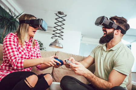 Happy friends playing video games with virtual reality glasses - Young people having fun with new technology console onlineの写真素材