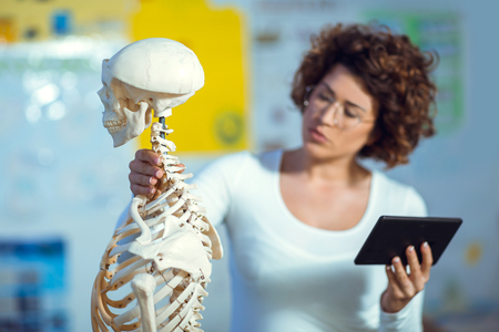 Medical doctor woman teaching anatomy using human skeleton modelの写真素材
