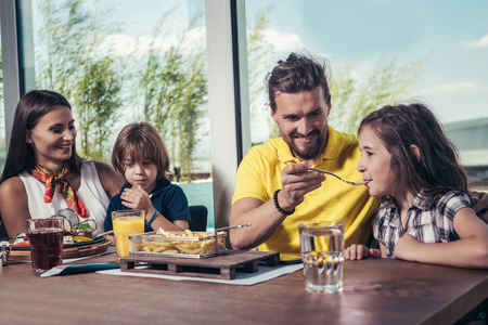 Father and mother with children enjoying meal in restaurant.の写真素材