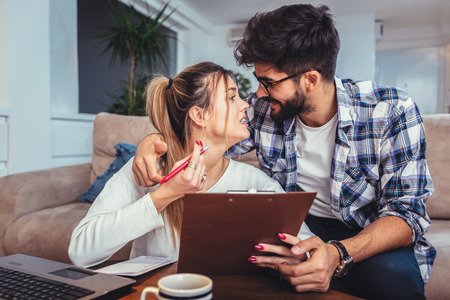Woman and man doing paperwork together, paying taxes online on notebook pcの写真素材