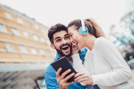 Couple sharing music and singing with a tablet. They smile, watching the funny video.の写真素材