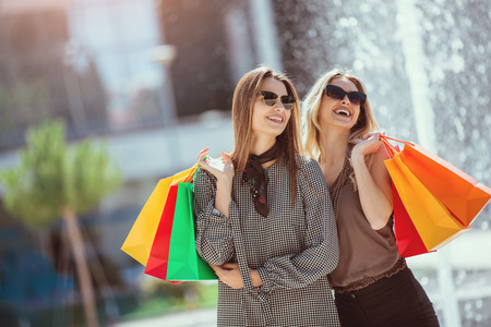 Happy friends shopping. Young friends enjoying shopping in the city, holding shopping bags.の写真素材
