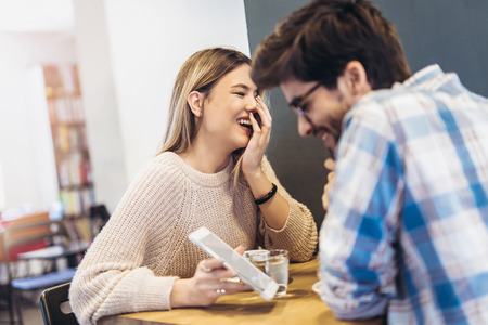 Young couple in indoor cafe using digital tablet and having fun.の写真素材