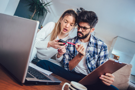 Woman and man doing paperwork together, paying taxes online on laptopの写真素材