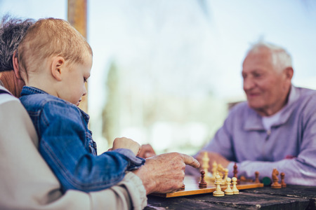 Active retired people, old friends and free time, two senior men having fun and playing chess at...
