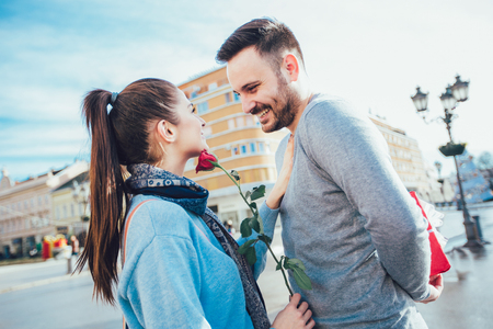Man surprises woman with a gift and rose in the cityの写真素材