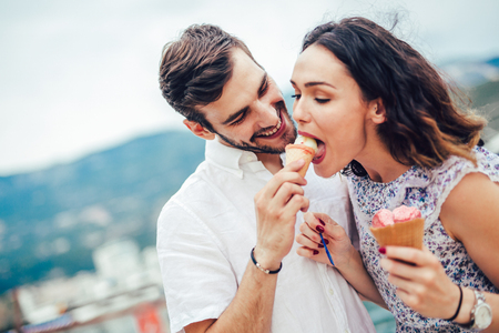 Happy couple having date and eating ice cream on vacation. Sea background.の写真素材