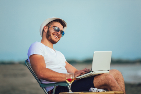 Man working with computer on the beach. Freelancer workingの写真素材