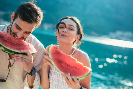 Cheerful couple holding slices of watermelonの写真素材