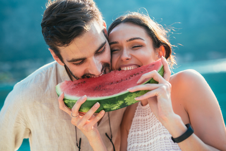 Cheerful couple holding slices of watermelonの写真素材