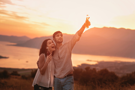 Portrait of young couple having good times in nature behind them is a beautiful sunset over Boka Bayの写真素材