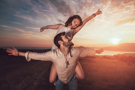 Young couple having having fun in nature, behind them is a beautiful sunset over Boka Bayの写真素材