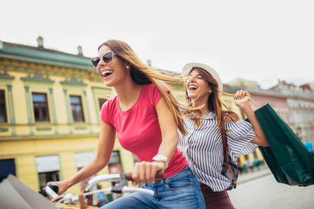 Two beautiful blonde women shopping on bike in the cityの写真素材