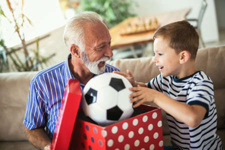 Handsome senior grandfather presenting gift to happy grandson