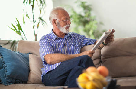 Senior man at home reading newspaper