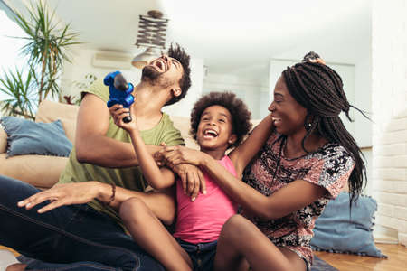 Smiling family sitting on the couch together playing video gamesの写真素材