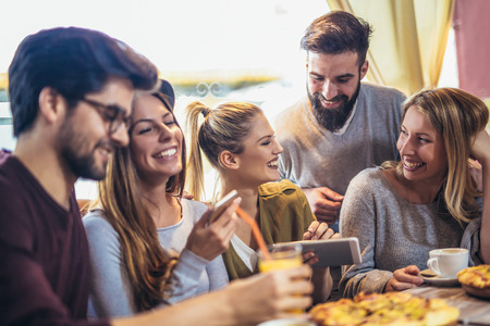Young friends sharing pizza in a indoor cafeの写真素材