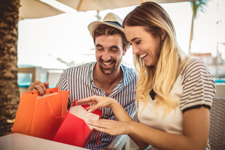 Beautiful loving couple sitting in a cafe enjoying in coffee and conversation after shoppingの写真素材