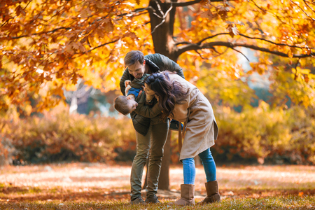 Young family having fun in the autumn park with his son.の写真素材