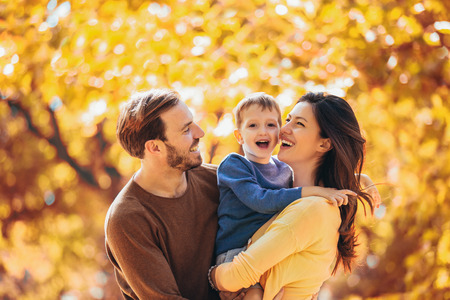 Young family having fun in the autumn park with his son.