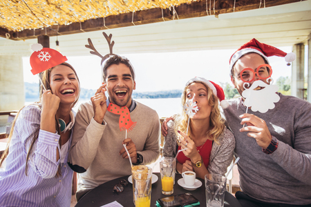 Cheerful group of friends having fun in cafe holding artificial mustache and lips stickの写真素材
