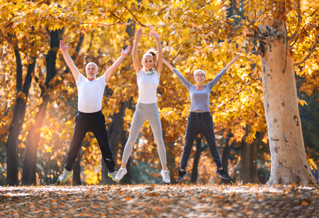 Senior man and woman and young female instructor  workout on fresh air. Outdoor activities, healthy lifestyle, strong bodies, fit figures. Stylish, modern sportswear. Different generationsの写真素材