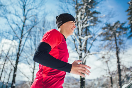 Young man running at winter in park