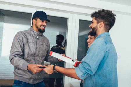 Friendly Delivery Man Handing Pizza To A Customerの写真素材