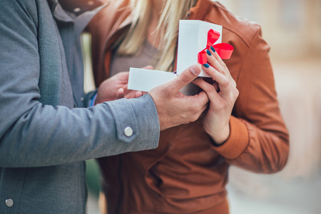 Couple in love.Man surprising his girlfriend with a gift, close up.の写真素材