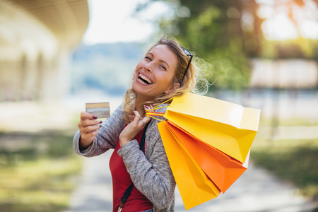 Young beautiful woman holding shopping bags and a credit cardの写真素材