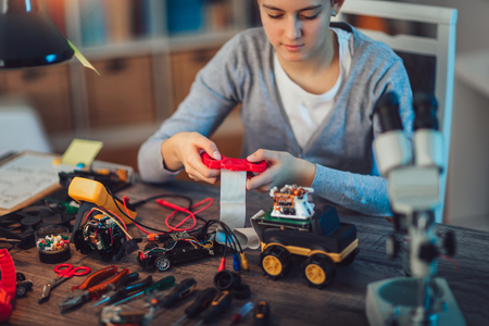 Girl constructs technical toy. Technical toy on table full of detailsの写真素材