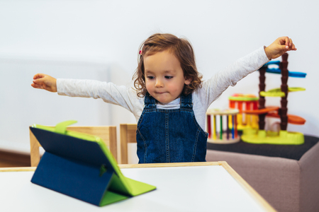Little girl playing with a digital tablet at home, selective focus.の写真素材