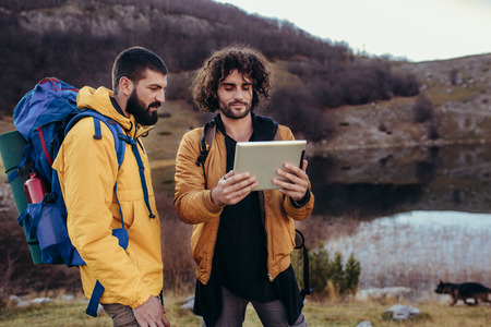 Lost hiker looking at the way through map on digital tablet during hiking in wildernessの写真素材