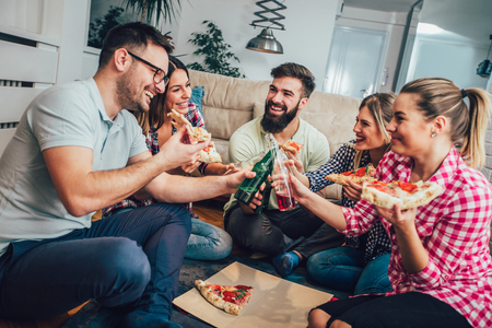 Group of young friends eating pizza.Home party.Fast food concept.の写真素材