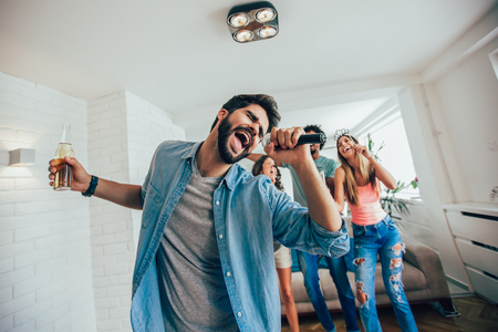 Group of friends playing karaoke at home. Concept about friendship, home entertainment and peopleの写真素材