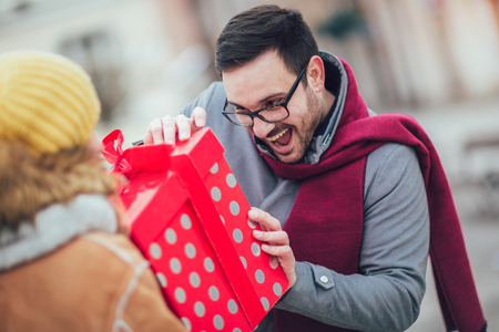 Woman giving man a surprise giftの写真素材