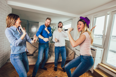 Group of friends playing karaoke at home. Concept about friendship, home entertainment and peopleの写真素材