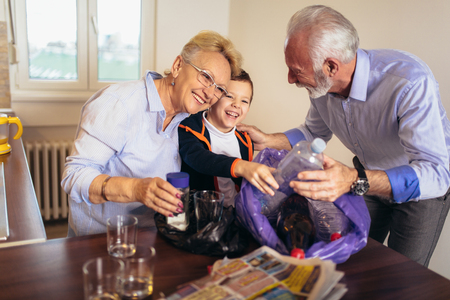 Boy with grandparents separating recyclable trash at homeの写真素材