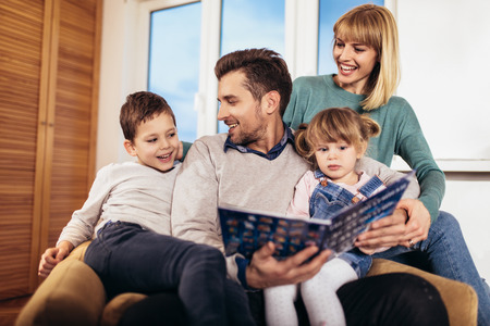 Happy family reading book at home, selective focus.