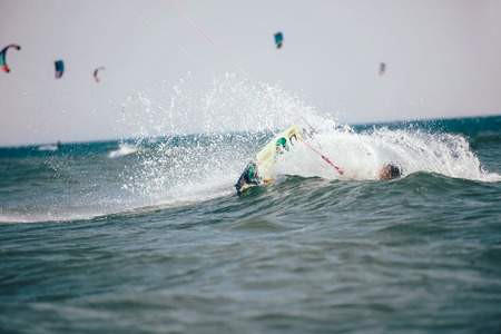 Professional kiter makes the difficult trick on a beautiful background. Kitesurfing Kiteboarding action photos man among waves quickly goesの写真素材