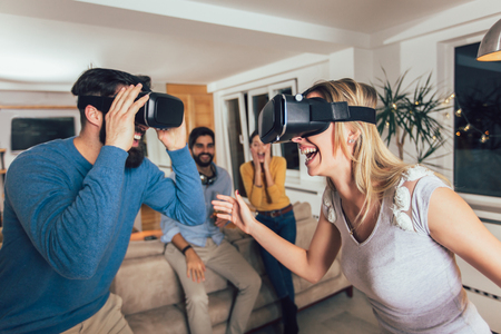 Young couple having fun with virtual reality headset glasses - Happy people playing game with new trends technologyの写真素材