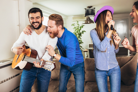 Group of friends playing karaoke at home. Concept about friendship, home entertainment and peopleの写真素材