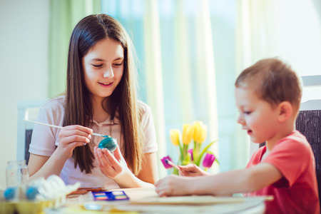 Children painted Easter eggs at the tableの写真素材